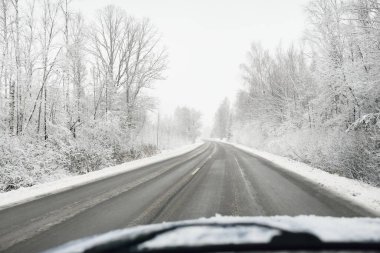 Boş otoyol (asfalt yol) karla kaplı ormanın içinden, kırsal alanda. Arabadan bak. Avrupa. Doğa, Noel tatilleri, uzak yerler, kış lastikleri, tehlikeli sürüş konsepti