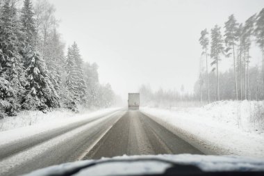 Boş otoyol (asfalt yol) karla kaplı ormanın içinden, kırsal alanda. Arabadan bak. Avrupa. Doğa, Noel tatilleri, uzak yerler, kış lastikleri, tehlikeli sürüş konsepti