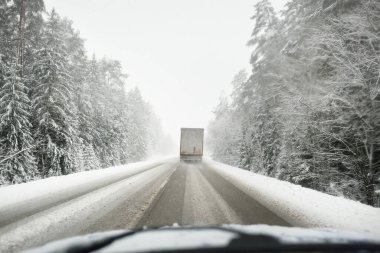 Boş otoyol (asfalt yol) karla kaplı ormanın içinden, kırsal alanda. Arabadan bak. Avrupa. Doğa, Noel tatilleri, uzak yerler, kış lastikleri, tehlikeli sürüş konsepti