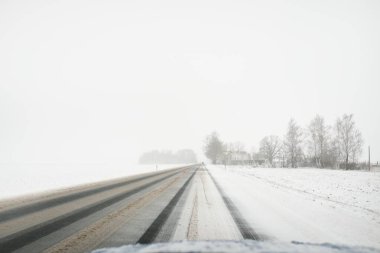 Karla kaplı orman ve kırsal alanda boş otoyol (asfalt yol). Kar fırtınası, kar yağışı. Avrupa. Doğa, Noel tatilleri, uzak yerler, kış lastikleri, tehlikeli sürüş konsepti