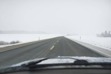 Karla kaplı orman ve kırsal alanda boş otoyol (asfalt yol). Kar fırtınası, kar yağışı. Avrupa. Doğa, Noel tatilleri, uzak yerler, kış lastikleri, tehlikeli sürüş konsepti