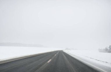 Karla kaplı orman ve kırsal alanda boş otoyol (asfalt yol). Kar fırtınası, kar yağışı. Avrupa. Doğa, Noel tatilleri, uzak yerler, kış lastikleri, tehlikeli sürüş konsepti
