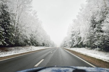 Boş otoyol (asfalt yol) karla kaplı ormanın içinden, kırsal alanda. Arabadan bak. Avrupa. Doğa, Noel tatilleri, uzak yerler, kış lastikleri, tehlikeli sürüş konsepti