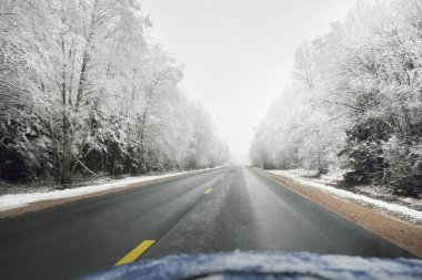 Karla kaplı ormanda boş otoyol (asfalt yol). Kanada mı? Doğa, Noel tatilleri, uzak yerler, kış lastikleri, tehlikeli sürüş konsepti