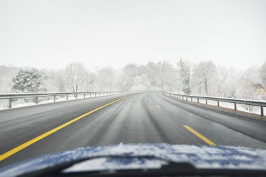 Karla kaplı ormanda boş otoyol (asfalt yol). Kanada mı? Doğa, Noel tatilleri, uzak yerler, kış lastikleri, tehlikeli sürüş konsepti