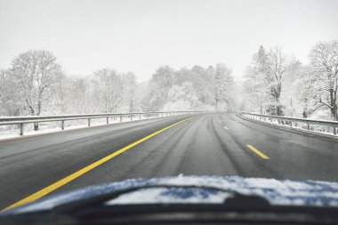 Karla kaplı ormanda boş otoyol (asfalt yol). Kanada mı? Doğa, Noel tatilleri, uzak yerler, kış lastikleri, tehlikeli sürüş konsepti