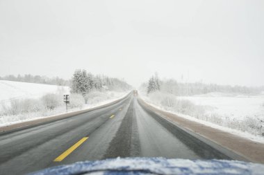 Karla kaplı orman ve arazide boş otoyol (asfalt yol). ABD. Doğa, Noel tatilleri, uzak yerler, kış lastikleri, tehlikeli sürüş konsepti