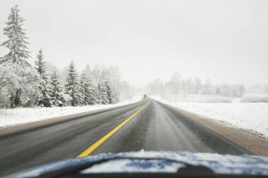 Karla kaplı orman ve arazide boş otoyol (asfalt yol). ABD. Doğa, Noel tatilleri, uzak yerler, kış lastikleri, tehlikeli sürüş konsepti
