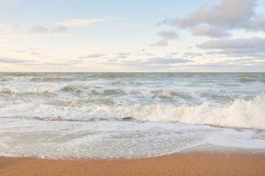 Gün batımında Baltık kıyıları (kum tepeleri). Yumuşak güneş ışığı, parlayan bulutlar, dalgalar ve su fışkıran berrak gökyüzü. Idyllic deniz manzarası. Liepaja, Letonya, Avrupa. Sıcak kış havası, iklim değişikliği, doğa