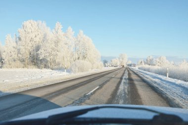 Karla kaplı orman ve kırsal alanda boş otoyol (asfalt yol). Kar sürükleniyor. Avrupa. Doğa, Noel tatilleri, uzak yerler, kış lastikleri, tehlikeli sürüş konsepti