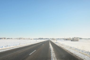 Karla kaplı orman ve kırsal alanda boş otoyol (asfalt yol). Kar sürükleniyor. Avrupa. Doğa, Noel tatilleri, uzak yerler, kış lastikleri, tehlikeli sürüş konsepti