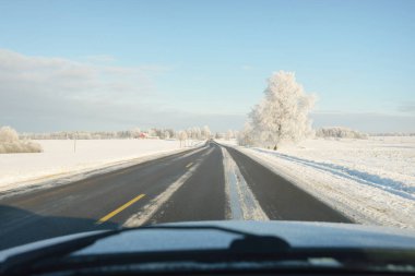 Karla kaplı orman ve kırsal alanda boş otoyol (asfalt yol). Kar sürükleniyor. Avrupa. Doğa, Noel tatilleri, uzak yerler, kış lastikleri, tehlikeli sürüş konsepti