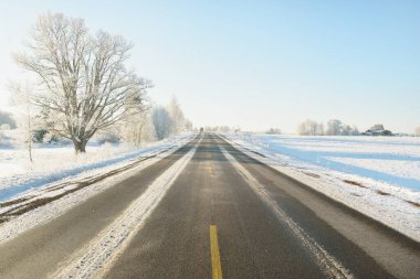 Karla kaplı orman ve kırsal alanda boş otoyol (asfalt yol). Kar sürükleniyor. Avrupa. Doğa, Noel tatilleri, uzak yerler, kış lastikleri, tehlikeli sürüş konsepti