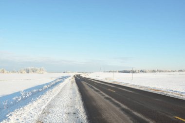 Karla kaplı orman ve kırsal alanda boş otoyol (asfalt yol). Kar sürükleniyor. Avrupa. Doğa, Noel tatilleri, uzak yerler, kış lastikleri, tehlikeli sürüş konsepti
