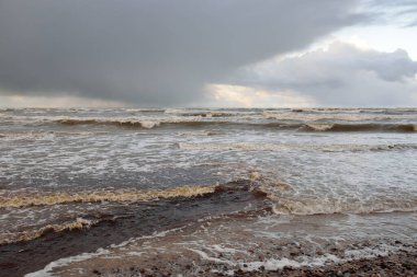 Gün batımında Baltık kıyısı. Kumsal, kum tepeleri. Dramatik gökyüzü akan bulutlar. Yumuşak güneş ışığı. Doğa, hava, çevre, eko turizm