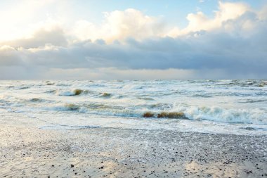 Fırtınadan sonra Baltık Denizi. Dramatik gökyüzü, parlayan bulutlar, yumuşak güneş ışığı. Dalgalar, su sıçratma. Resimli manzara, deniz manzarası, doğa. Panoramik görünüm