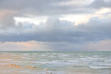 Fırtınadan sonra Baltık Denizi. Dramatik gökyüzü, parlayan bulutlar, yumuşak güneş ışığı. Dalgalar, su sıçratma. Resimli manzara, deniz manzarası, doğa. Panoramik görünüm