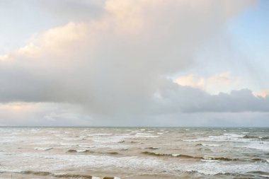 Fırtınadan sonra Baltık Denizi. Dramatik gökyüzü, parlayan bulutlar, yumuşak güneş ışığı. Dalgalar, su sıçratma. Resimli manzara, deniz manzarası, doğa. Panoramik görünüm