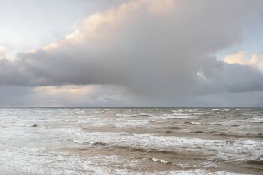 Fırtınadan sonra Baltık Denizi. Dramatik gökyüzü, parlayan bulutlar, yumuşak güneş ışığı. Dalgalar, su sıçratma. Resimli manzara, deniz manzarası, doğa. Panoramik görünüm
