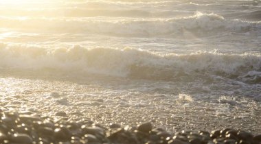 Fırtınadan sonra Baltık kıyıları. Gün batımı, yumuşak güneş ışığı. Su yüzeyi dokusu, çarpan dalgalar, sıçramalar, köpük. Resimli panoramik manzara. Idyllic deniz manzarası. Doğa, çevre, ekoloji temaları
