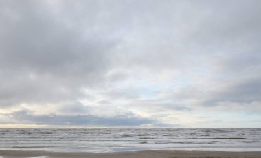 Fırtınadan sonra Baltık Denizi. Yumuşak günbatımı ışığı, çarpıcı parlayan bulutlar. Deniz manzarası, bulutlar, doğa. Panoramik manzara. Ekoloji, iklim değişikliği, hava durumu