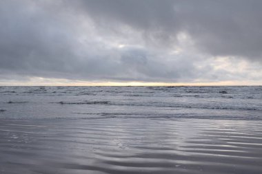 Fırtınadan sonra Baltık Denizi. Yumuşak günbatımı ışığı, çarpıcı parlayan bulutlar. Deniz manzarası, bulutlar, doğa. Sudaki yansımalar. Panoramik manzara. Ekoloji, iklim değişikliği, hava durumu