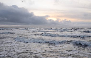 Fırtınadan sonra Baltık Denizi. Yumuşak günbatımı ışığı, çarpıcı parlayan bulutlar. Deniz manzarası, bulutlar, doğa. Panoramik manzara. Ekoloji, iklim değişikliği, hava durumu