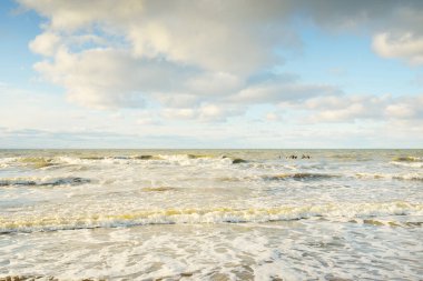Kumlu bir sahilden (kum tepeleri) Baltık denizinin panoramik görüntüsü. Parlayan bulutlarla, dalgalarla ve su sıçramalarıyla berrak bir gökyüzü. Idyllic deniz manzarası. Sıcak kış havası, iklim değişikliği, doğa