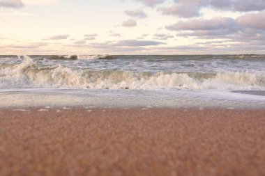 Gün batımında Baltık kıyıları (kum tepeleri). Yumuşak güneş ışığı, parlayan bulutlar, dalgalar ve su fışkıran berrak gökyüzü. Idyllic deniz manzarası. Liepaja, Letonya, Avrupa. Sıcak kış havası, iklim değişikliği, doğa