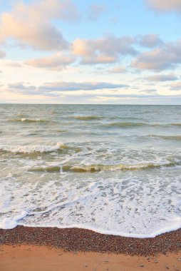 Gün batımında Baltık kıyıları (kum tepeleri). Yumuşak güneş ışığı, parlayan bulutlar, dalgalar ve su fışkıran berrak gökyüzü. Idyllic deniz manzarası. Liepaja, Letonya, Avrupa. Sıcak kış havası, iklim değişikliği, doğa