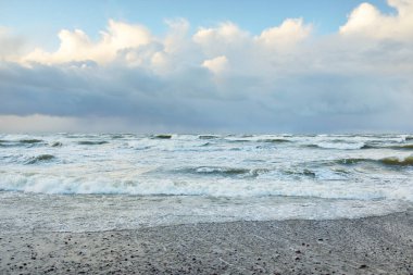 Fırtınadan sonra Baltık Denizi. Dramatik gökyüzü, parlayan bulutlar, yumuşak güneş ışığı. Dalgalar, su sıçratma. Resimli manzara, deniz manzarası, doğa. Panoramik görünüm