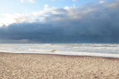 Fırtınadan sonra Baltık kıyıları (kum tepeleri, plaj). Dramatik gökyüzü, parlayan bulutlar. Resimli panoramik manzara. Doğa, çevre, ekoloji, eko-turizm, yürüyüş, keşif kavramları