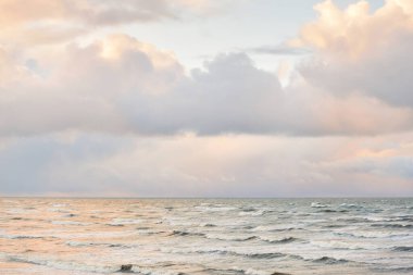 Fırtınadan sonra Baltık Denizi. Dramatik gökyüzü, parlayan bulutlar, yumuşak güneş ışığı. Dalgalar, su sıçratma. Resimli manzara, deniz manzarası, doğa. Panoramik görünüm