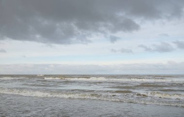 Kumlu bir sahilden (kum tepeleri) Baltık denizinin panoramik görüntüsü. Koyu bulutlu dramatik bir gökyüzü. Dalgalar, su sıçramaları. Idyllic deniz manzarası. Sıcak kış havası, iklim değişikliği, doğa. Danimarka
