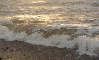 Fırtınadan sonra Baltık kıyıları. Gün batımı, yumuşak güneş ışığı. Su yüzeyi dokusu, çarpan dalgalar, sıçramalar, köpük. Resimli panoramik manzara. Idyllic deniz manzarası. Doğa, çevre, ekoloji temaları