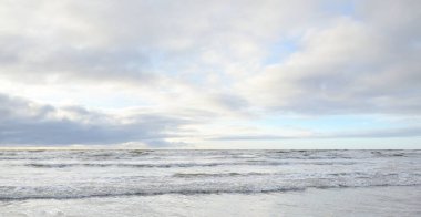 Fırtınadan sonra Baltık Denizi. Yumuşak günbatımı ışığı, çarpıcı parlayan bulutlar. Deniz manzarası, bulutlar, doğa. Panoramik manzara. Ekoloji, iklim değişikliği, hava durumu