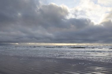 Fırtınadan sonra Baltık Denizi. Yumuşak günbatımı ışığı, çarpıcı parlayan bulutlar. Deniz manzarası, bulutlar, doğa. Sudaki yansımalar. Panoramik manzara. Ekoloji, iklim değişikliği, hava durumu