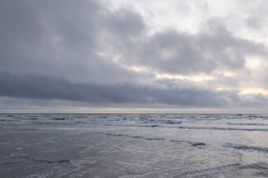 Fırtınadan sonra Baltık Denizi. Yumuşak günbatımı ışığı, çarpıcı parlayan bulutlar. Deniz manzarası, bulutlar, doğa. Panoramik manzara. Ekoloji, iklim değişikliği, hava durumu