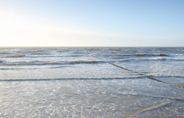 Gün batımında Baltık kıyısı. Yumuşak altın güneş ışığı, parlayan gökyüzü, dalgalar. Idyllic deniz manzarası. Seyahat yerleri, eko turizm, doğa, hava durumu, iklim değişikliği. Resimli panoramik manzara