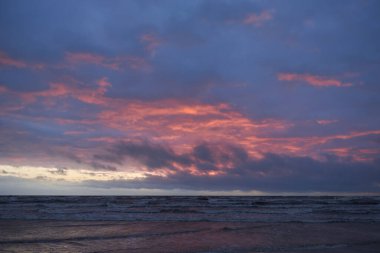 Fırtınadan sonra gün batımında Baltık Denizi. Dramatik gökyüzü, parlayan bulutlar, dofty altın güneş ışığı, dalgalar, fışkıran su. Resimli panoramik manzara. Doğa, çevre, ekoloji