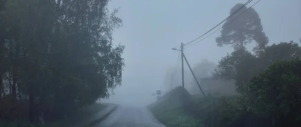 一个空旷的乡间柏油路穿过树林和村庄 在一个下雨天的大雾中 乌云密布的天空 公路旅行 — 图库照片