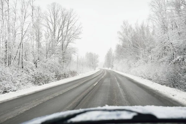 Boş otoyol (asfalt yol) karla kaplı ormanın içinden, kırsal alanda. Arabadan bak. Avrupa. Doğa, Noel tatilleri, uzak yerler, kış lastikleri, tehlikeli sürüş konsepti