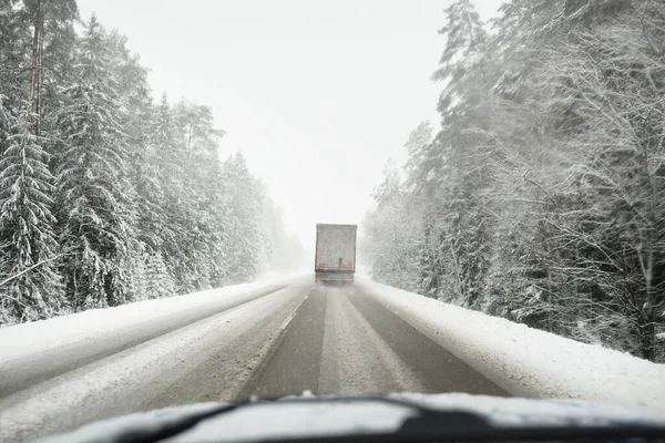 Boş otoyol (asfalt yol) karla kaplı ormanın içinden, kırsal alanda. Arabadan bak. Avrupa. Doğa, Noel tatilleri, uzak yerler, kış lastikleri, tehlikeli sürüş konsepti