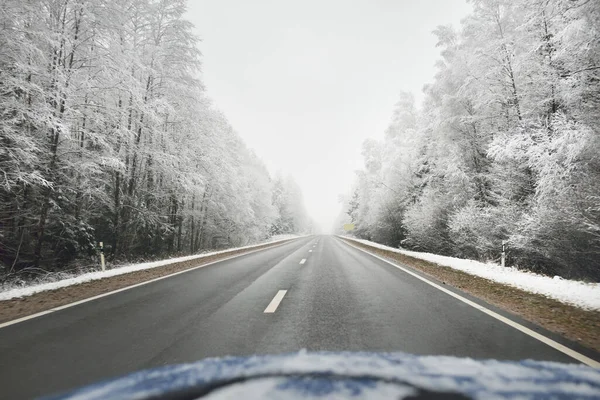 Boş otoyol (asfalt yol) karla kaplı ormanın içinden, kırsal alanda. Arabadan bak. Avrupa. Doğa, Noel tatilleri, uzak yerler, kış lastikleri, tehlikeli sürüş konsepti