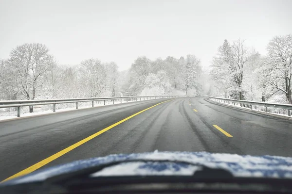 Karla kaplı ormanda boş otoyol (asfalt yol). Kanada mı? Doğa, Noel tatilleri, uzak yerler, kış lastikleri, tehlikeli sürüş konsepti