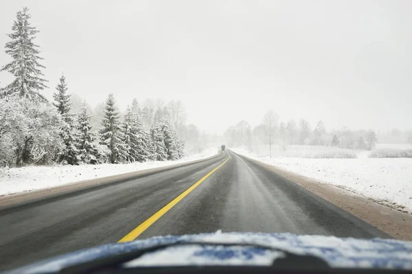 Karla kaplı orman ve arazide boş otoyol (asfalt yol). ABD. Doğa, Noel tatilleri, uzak yerler, kış lastikleri, tehlikeli sürüş konsepti