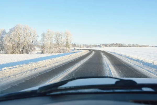Karla kaplı orman ve kırsal alanda boş otoyol (asfalt yol). Kar sürükleniyor. Avrupa. Doğa, Noel tatilleri, uzak yerler, kış lastikleri, tehlikeli sürüş konsepti