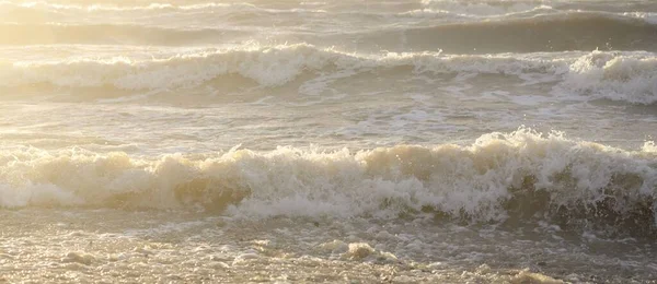 Fırtınadan sonra Baltık kıyıları. Gün batımı, yumuşak güneş ışığı. Su yüzeyi dokusu, çarpan dalgalar, sıçramalar, köpük. Resimli panoramik manzara. Idyllic deniz manzarası. Doğa, çevre, ekoloji temaları