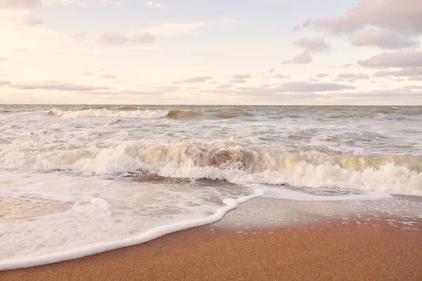 Gün batımında Baltık kıyıları (kum tepeleri). Yumuşak güneş ışığı, parlayan bulutlar, dalgalar ve su fışkıran berrak gökyüzü. Idyllic deniz manzarası. Liepaja, Letonya, Avrupa. Sıcak kış havası, iklim değişikliği, doğa