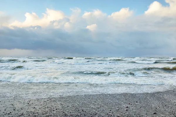 Fırtınadan sonra Baltık Denizi. Dramatik gökyüzü, parlayan bulutlar, yumuşak güneş ışığı. Dalgalar, su sıçratma. Resimli manzara, deniz manzarası, doğa. Panoramik görünüm